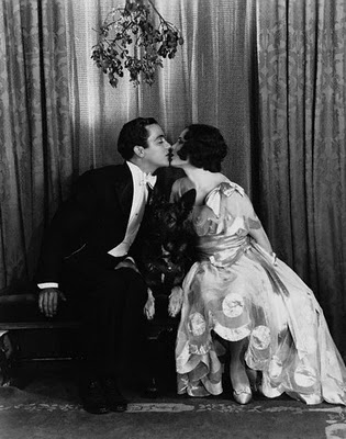 foto d'epoca che ritrae una coppia baciarsi sotto il vischio