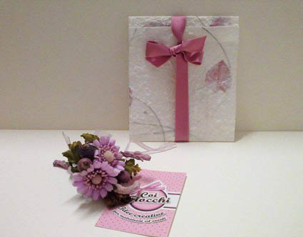 partecipazione di nozze fatta a mano in carta naturale con inserti di petali rosa e nastro di raso