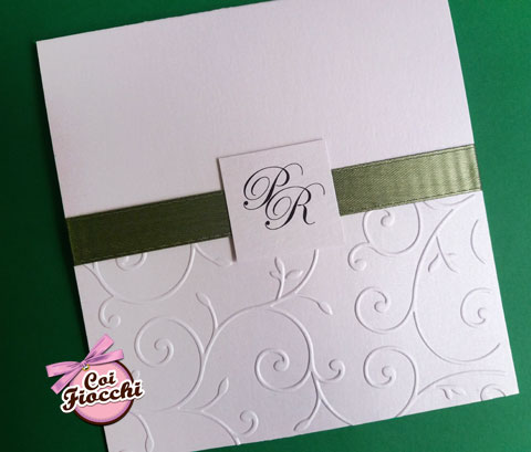 Partecipazione di matrimonio elegante in carta perlata con ghirigori a rilievo, nastro verde e tag con le iniziali degli sposi.