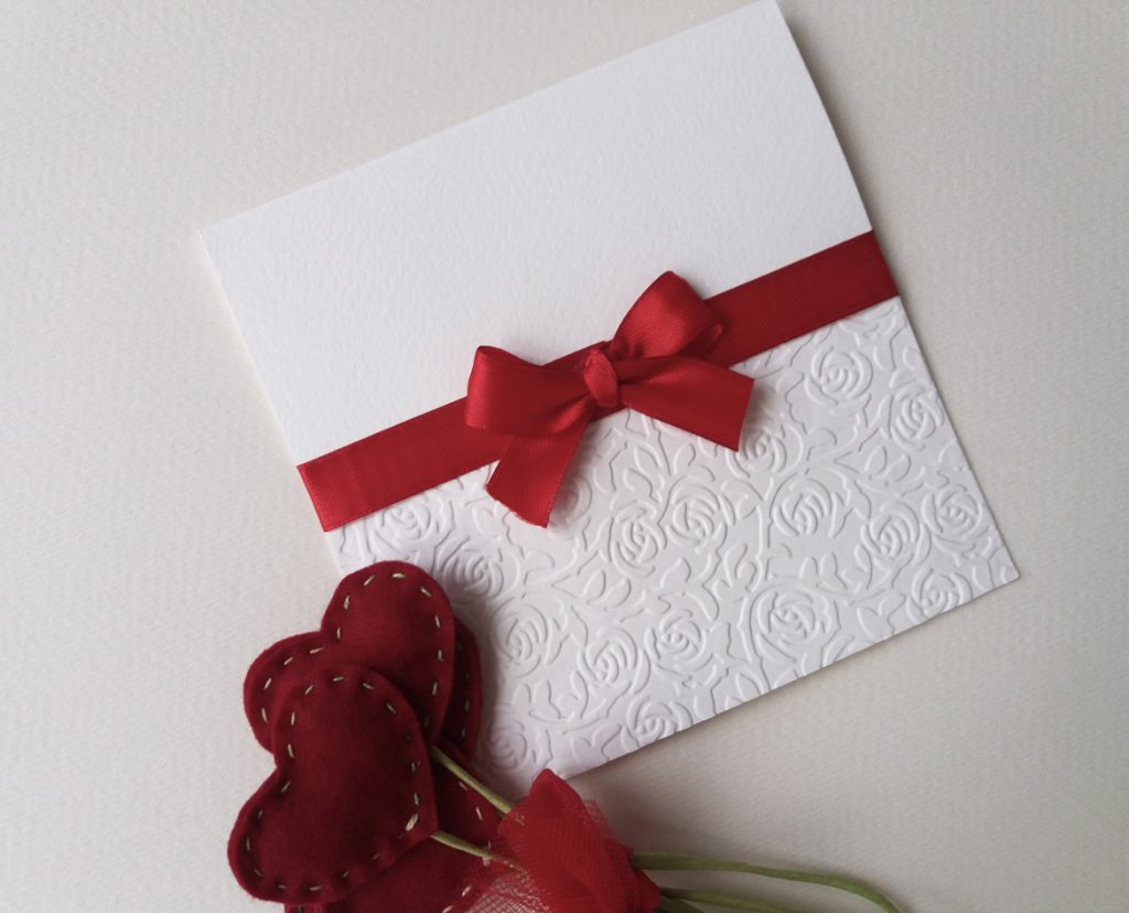 partecipazione di matrimonio elegante con rose a rilievo sulla carta e raso rosso